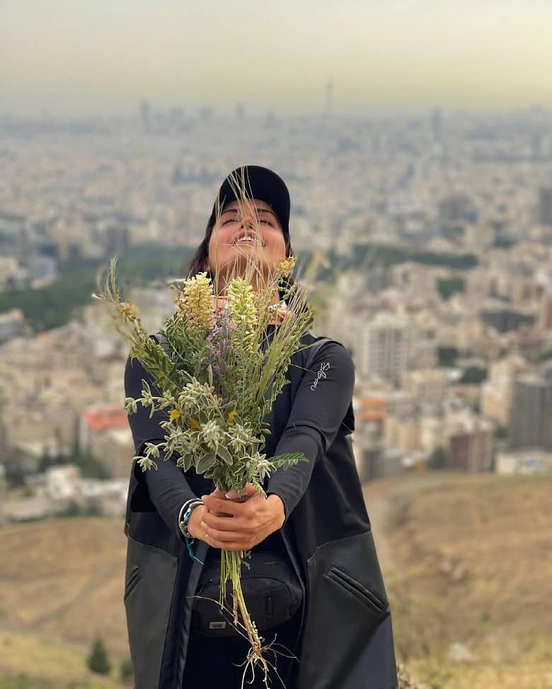 الناز شاکر دوست در حالی که گلی دستش گرفته و می خندد.